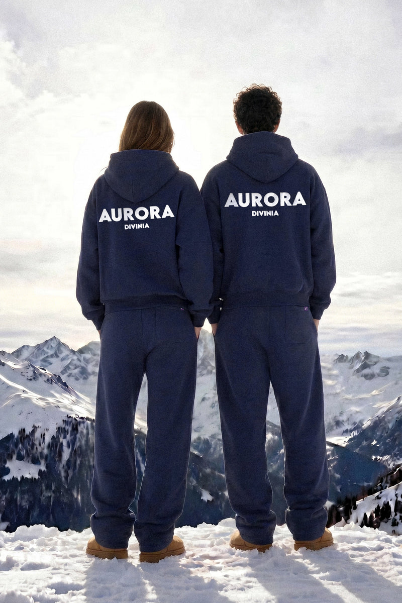 Two people wearing 'Aurora Divinia' branded outfits standing on a snowy mountain.
