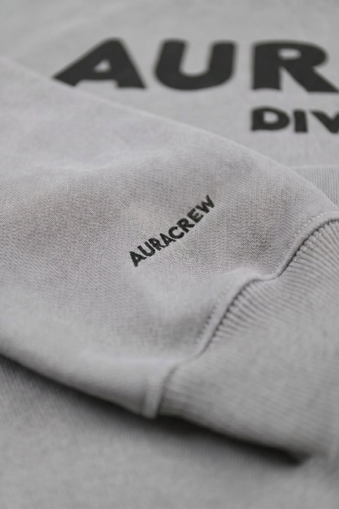 Gray sweatshirt with 'AURACREW' branding on a plain background