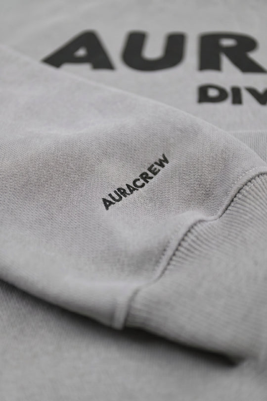 Gray sweatshirt with 'AURACREW' branding on a plain background