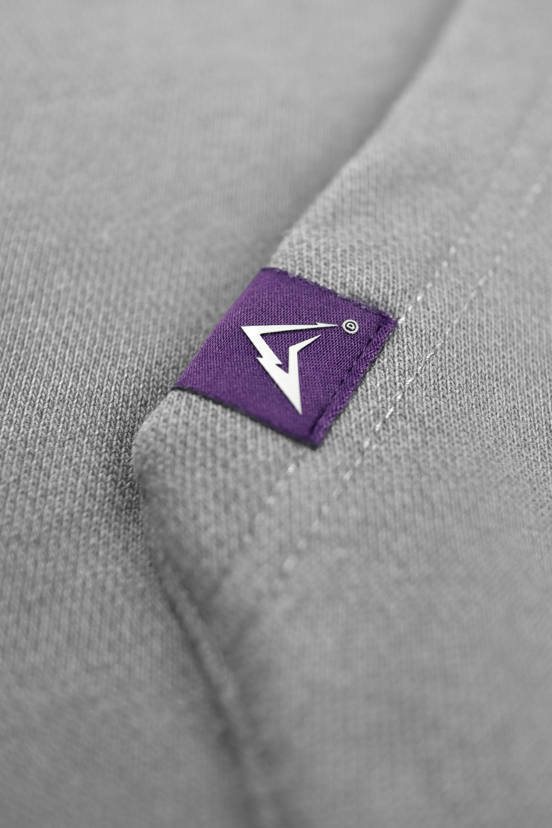Close-up of a gray garment with a purple label featuring a white logo.