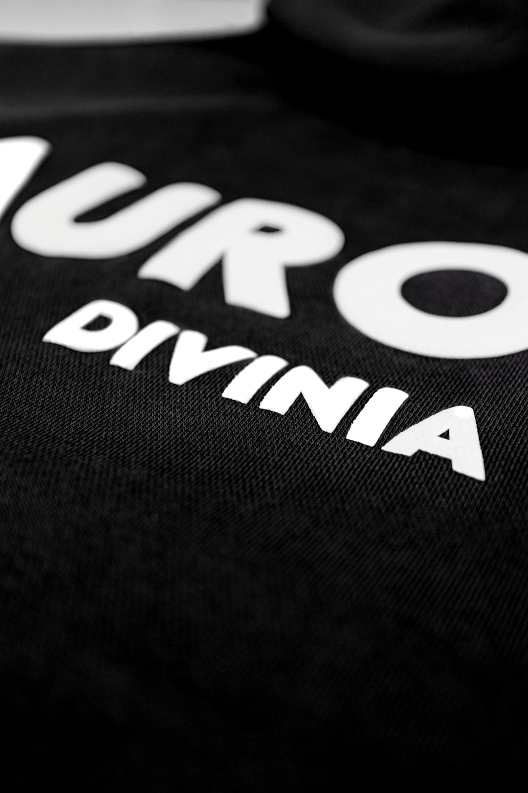 Black shirt with white text 'NURO' and 'DIVINIA' on a dark background