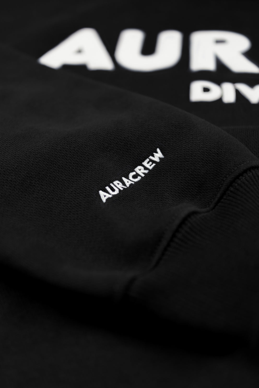 Black sweatshirt with 'AURCREW' branding on a dark background